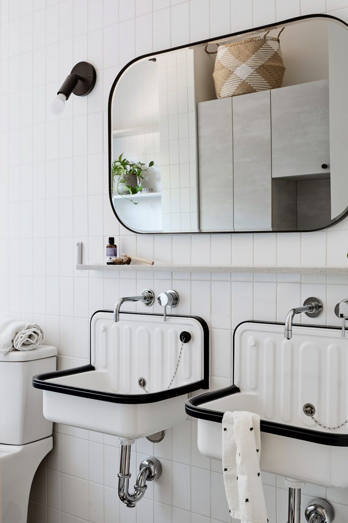 Two white and black bucket sinks in a white bathroom