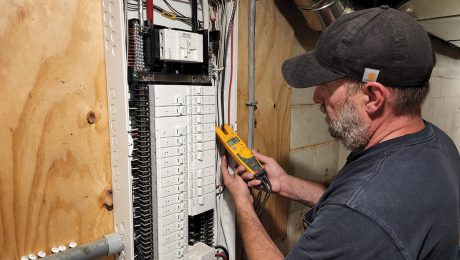 A man connecting an energy tracking monitor to an electrical service panel